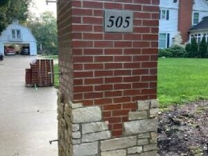 Brick and stone masonry pillar with address plaque.